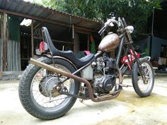 a motorcycle parked in front of a building with trees and other items on the ground