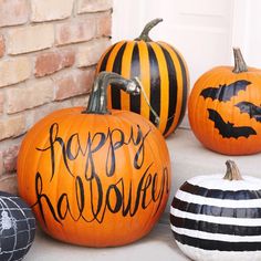 three pumpkins with happy halloween written on them are sitting in front of a door