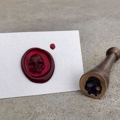 a wax stamp with a skull on it next to a piece of paper that has been turned red