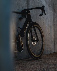 a bike leaning against a concrete wall with the sun shining on it's rims