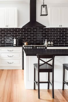 a kitchen with black and white tile backsplash, wood flooring and stools