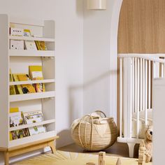 a baby's room with bookshelf, crib and teddy bear on the floor