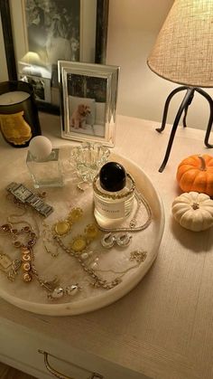 a white tray topped with jewelry next to a lamp