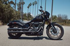 a black motorcycle parked on the side of a road next to palm tree's