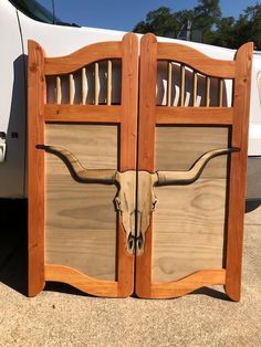 two wooden doors with longhorns on them in front of a white truck,