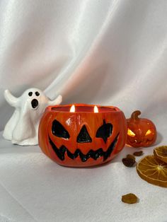 a halloween pumpkin candle holder with two jack - o'- lanterns in front of it