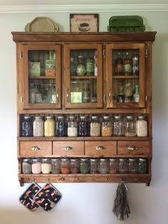 a wooden cabinet filled with lots of jars and spices next to a wall mounted spice rack