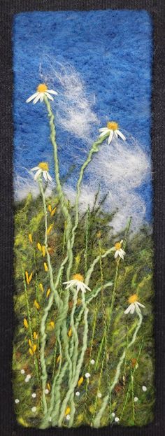 an image of flowers in the grass with blue sky and clouds behind it, made from felt