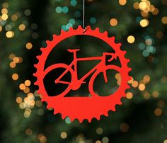 a red bicycle ornament hanging from a string with lights in the back ground