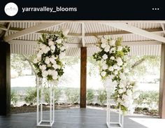 an outdoor ceremony with white flowers and greenery on the side of the aisle, in front of large windows