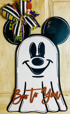 a mickey mouse door hanger with the name boo to you on it and a bow