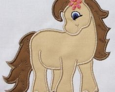 a close up of a small pony on a white shirt with pink flowers in it's hair