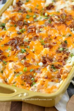 a casserole dish with bacon, cheese and green onions