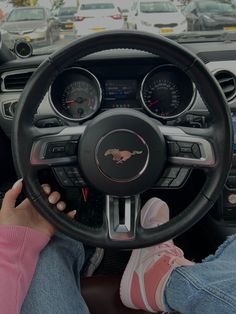 a person sitting in the driver's seat of a car with their feet on the steering wheel