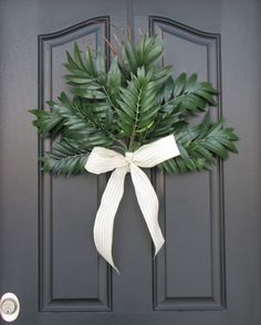 a wreath on the front door is adorned with green leaves and white ribbon for an elegant touch