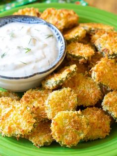 a green plate topped with fried food next to a small bowl of ranch dip on top of it