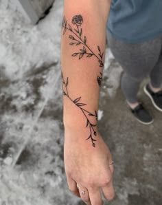 a woman's arm with a flower tattoo on the left side of her hand