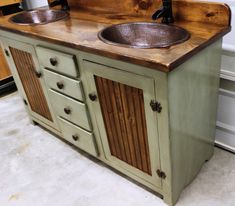 two sinks are on top of a green cabinet with wood trimmings and matching faucets