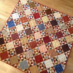 an old quilt is laying on the floor in front of a wood flooring area