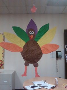 a turkey made out of paper sitting on top of a table in front of a wall