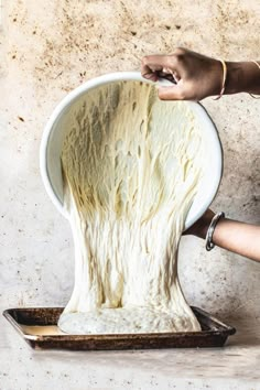 a person is making something out of dough on a tray with a spatula in their hand