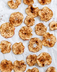 sliced apples are sitting on a piece of parchment paper with seasoning sprinkles