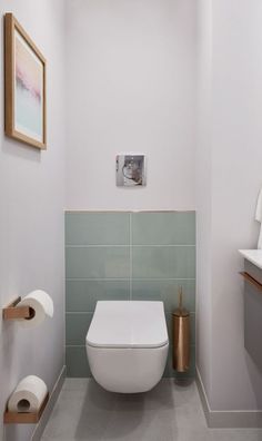 a white toilet sitting in a bathroom next to a wall mounted paper dispenser