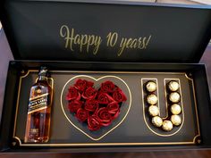 a bottle of whiskey and some chocolates in a gift box with roses on it