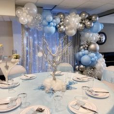 a table is set with silver and blue balloons