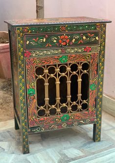 an ornately painted cabinet on display in a room with tile flooring and walls