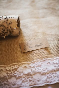 a piece of paper that is sitting on top of a lace covered table cloth with a tag