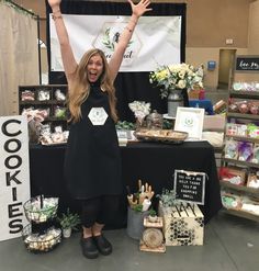 a woman standing in front of a table full of cakes and desserts with her hands up