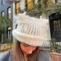 a woman wearing a white knitted hat while looking at her cell phone