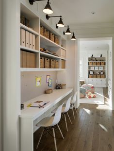 an office with white desks and shelves filled with books