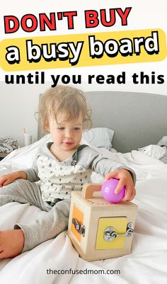 a little boy sitting on top of a bed next to a box with a toy in it