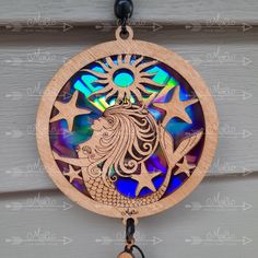 a wooden wind chime with an image of a mermaid on it's face