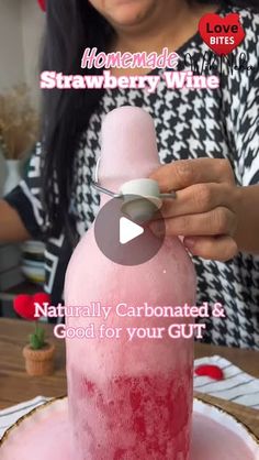 a woman is holding a pink bottle on top of a table