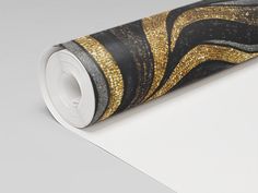 a roll of black and gold wallpaper sitting on top of a white flooring