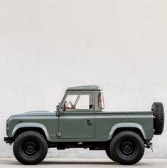 a green truck parked in front of a white wall