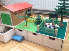 a toy farm with animals and trees on the table in front of it is a play house