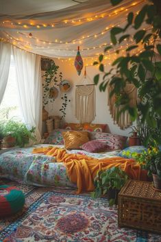 a bed with lots of pillows and blankets on top of it in a room filled with plants