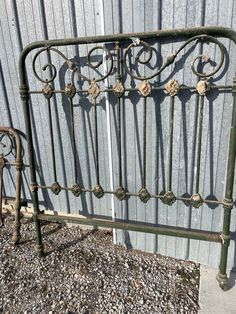 an old iron bed frame sitting in front of a building