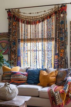 a living room filled with lots of colorful pillows and blankets on top of a white couch