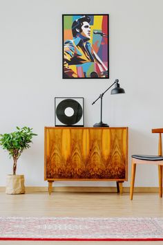 a living room with a painting on the wall next to a wooden cabinet and chair