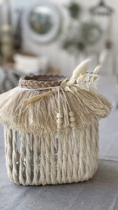 a white basket with some tassels on it sitting on top of a table