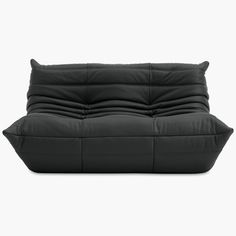 a black leather couch sitting on top of a white floor