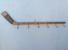 a hockey stick mounted to the side of a wall with hooks on it that says eat sleep play hockey