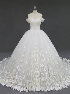 a white wedding dress with flowers on the skirt and off - shouldered neckline