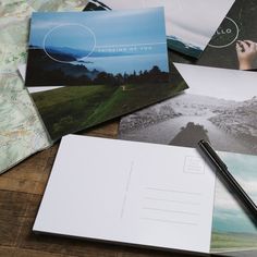 several postcards and a pen sitting on top of a wooden table next to each other