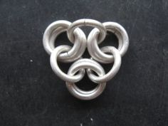 a silver brooch sitting on top of a black surface